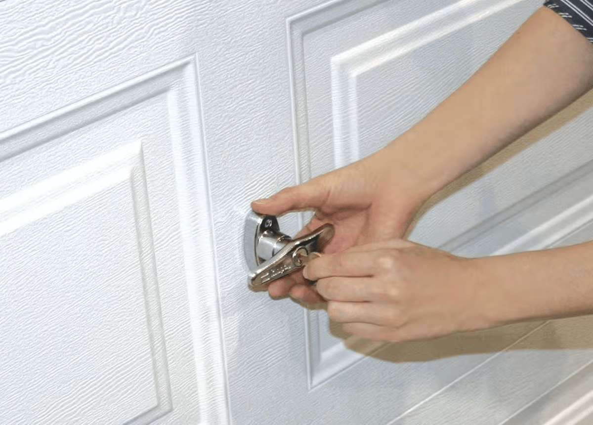 A person using a key to lock a garage door from the outside.