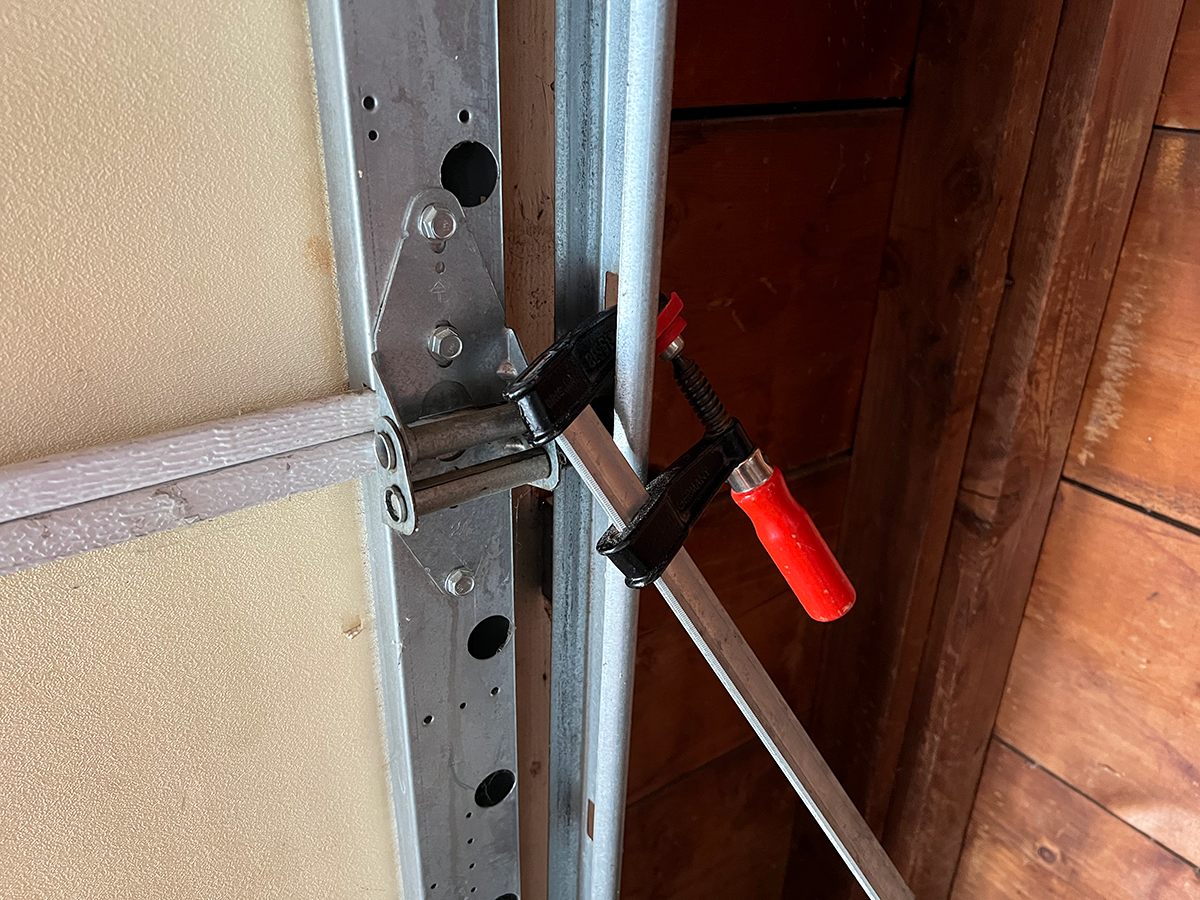 A garage door locked with a clamp attached to door tracks.