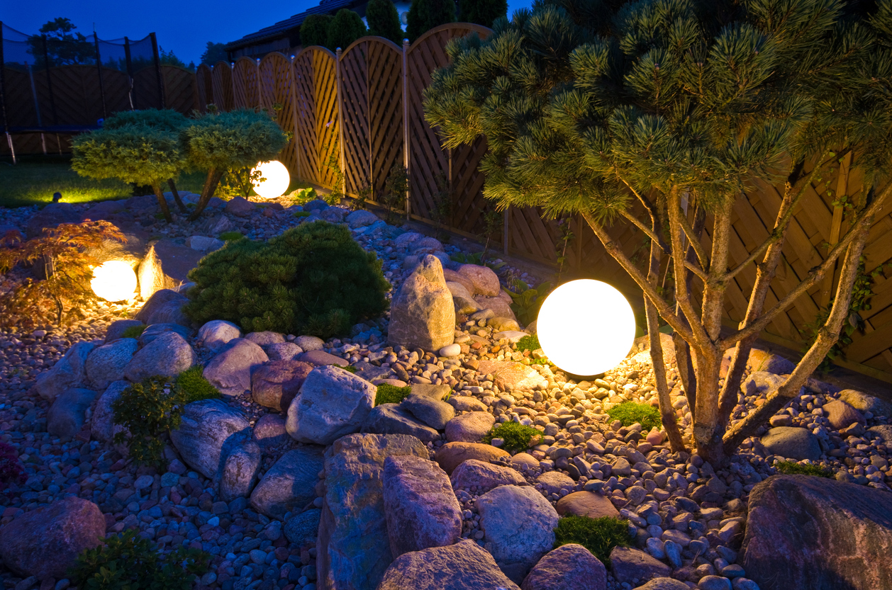 A rock garden illuminated by decorative globe-shaped lights.