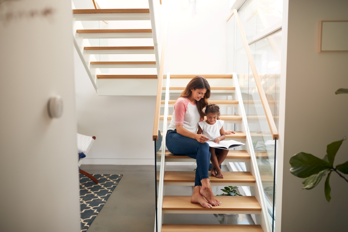 Mother and child sitting on staircase with book.