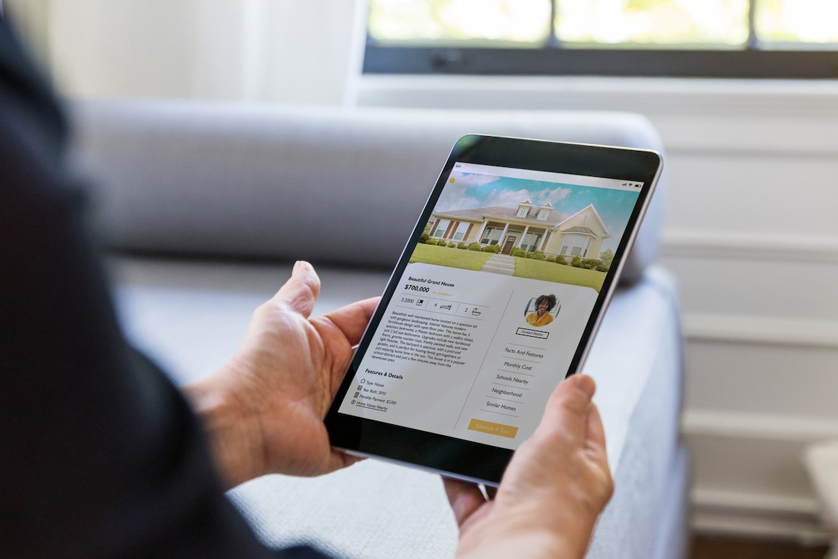 A person searching for homes for sale online using a digital tablet.