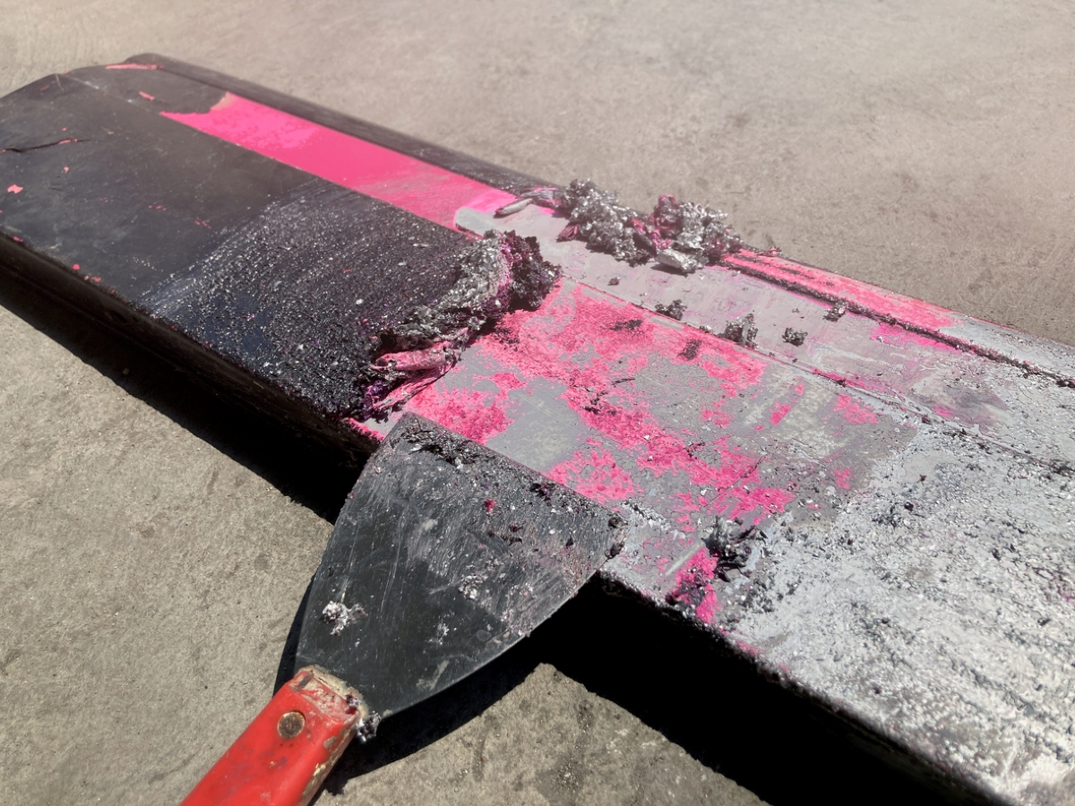 Paint scraper used to scrape dark paint on metal.