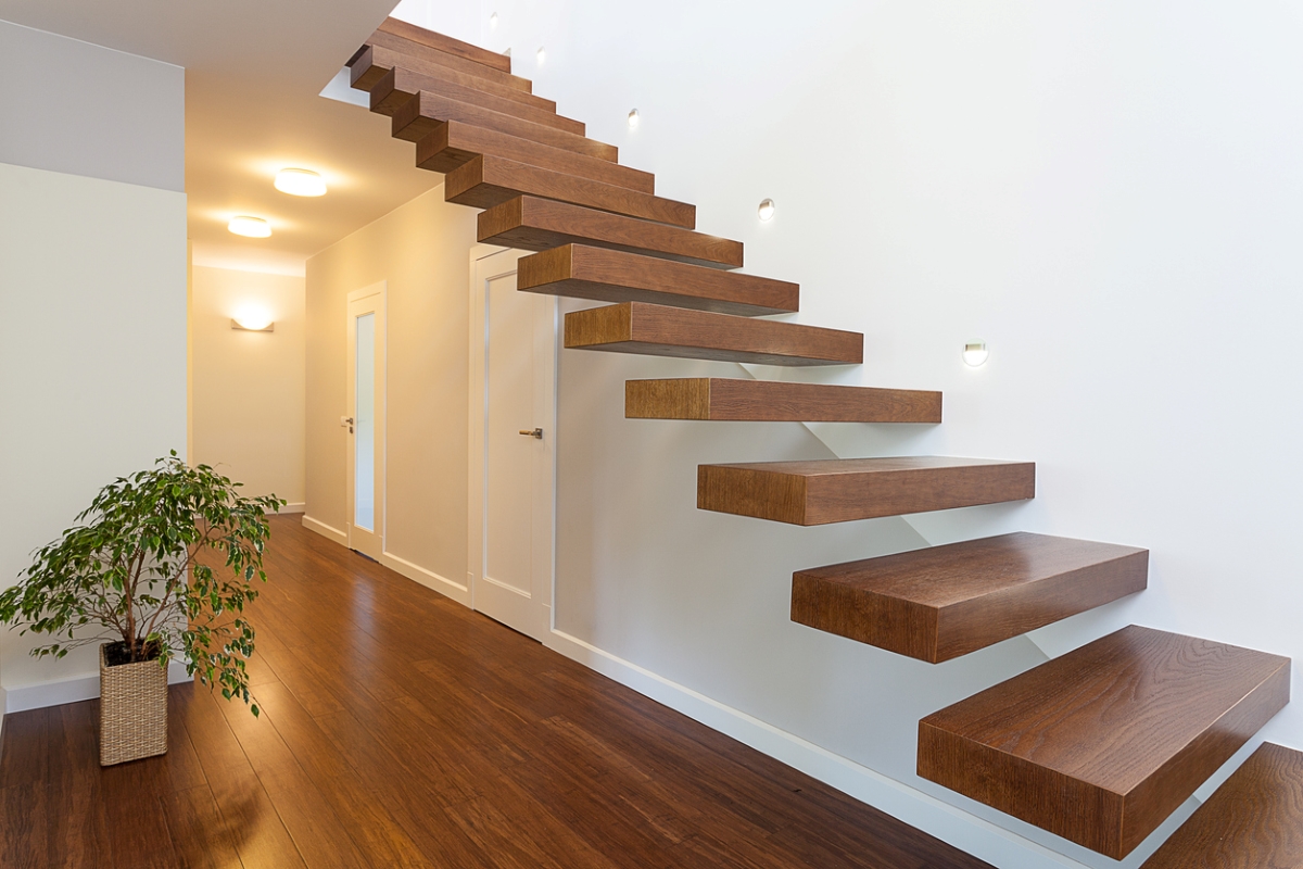 A floating walnut staircase in a modern hallway.