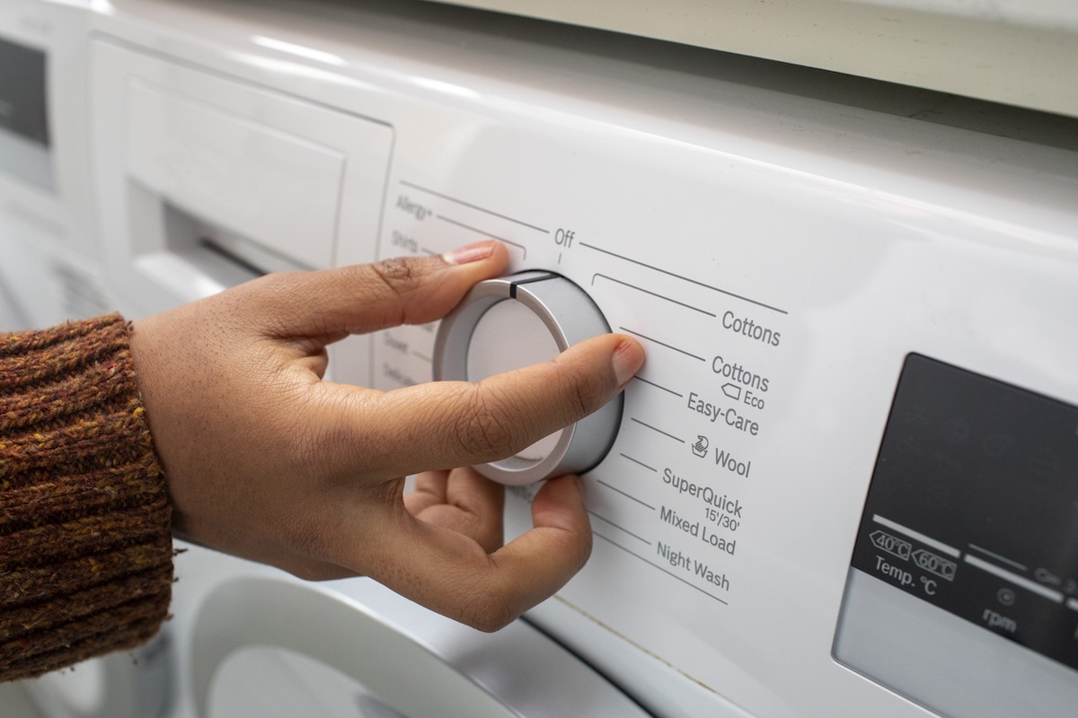 A person selecting a washing machine cycle learning how to do laundry the modern way.