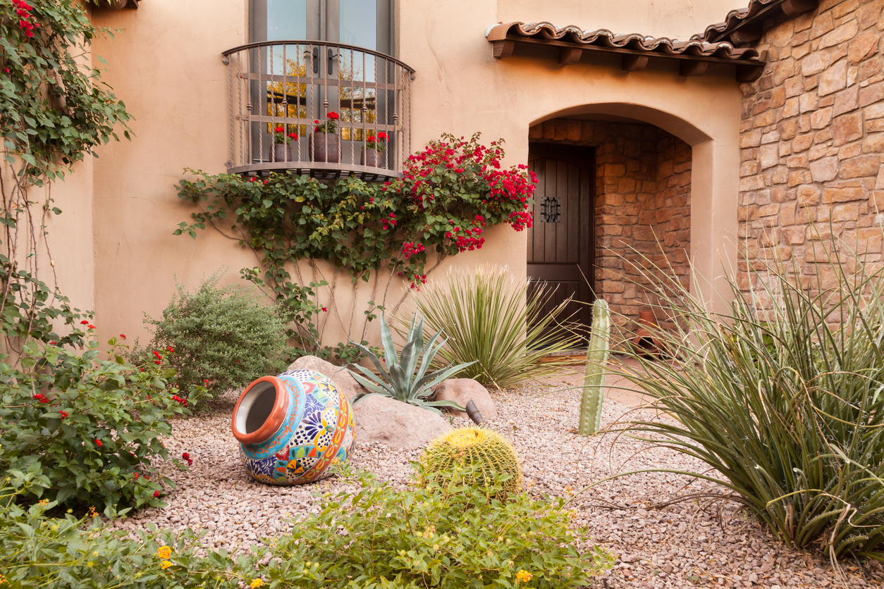 A Southwestern home courtyard consisting of a rock garden, ornamental native grasses, and a colorful pot.