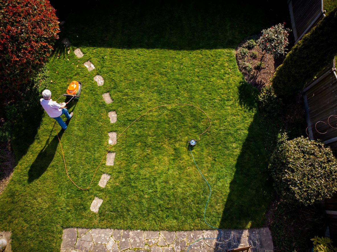 An overhead view of a person mowing a lawn. 