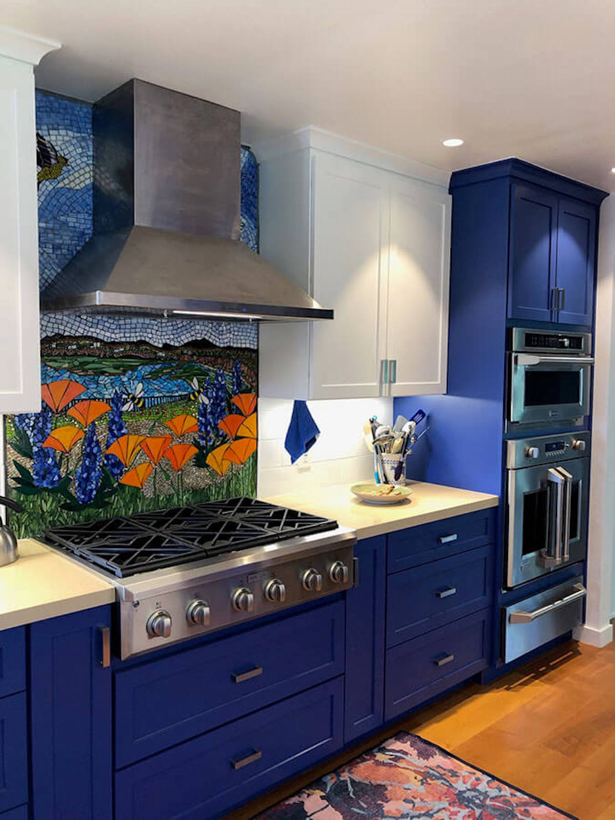 A blue and white themed kitchen featuring a meadow mosaic backsplash.