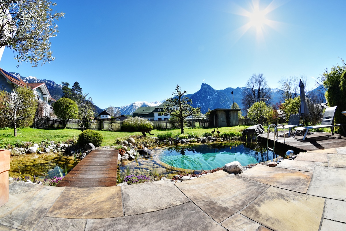 A natural swimming pool in backyard with mountain view.