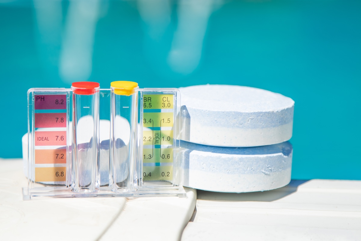 A pool cleaning and maintenance kit with chlorine tablets, with pool water in the background.