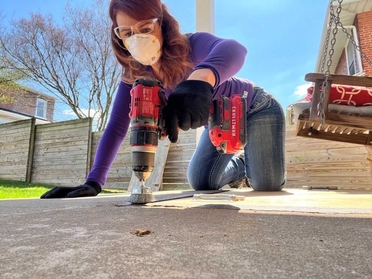 Woman using drill to remove paint from metal trim.
