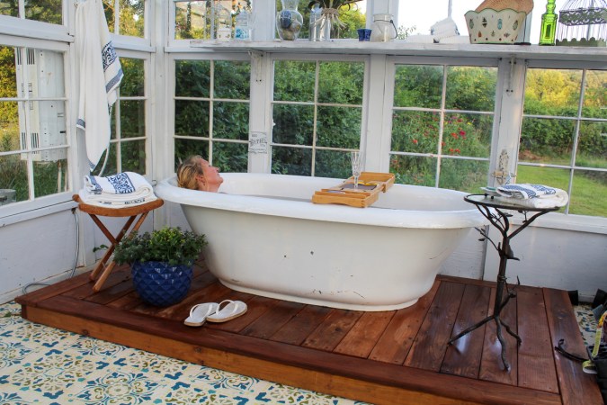 A person relaxing in the best soaking tub surrounded by windows.