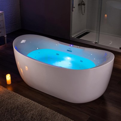 The Woodbridge Whirlpool Heated Soaking Bathtub filled with water in a tranquil, candle-lit bathroom.