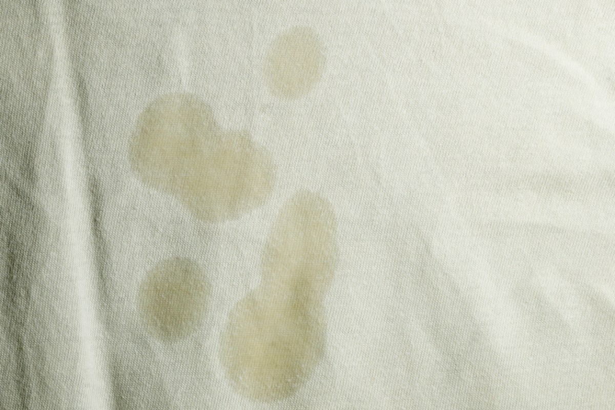 Cream-colored cotton fabric is laid flat to reveal a smattering of oil stains.