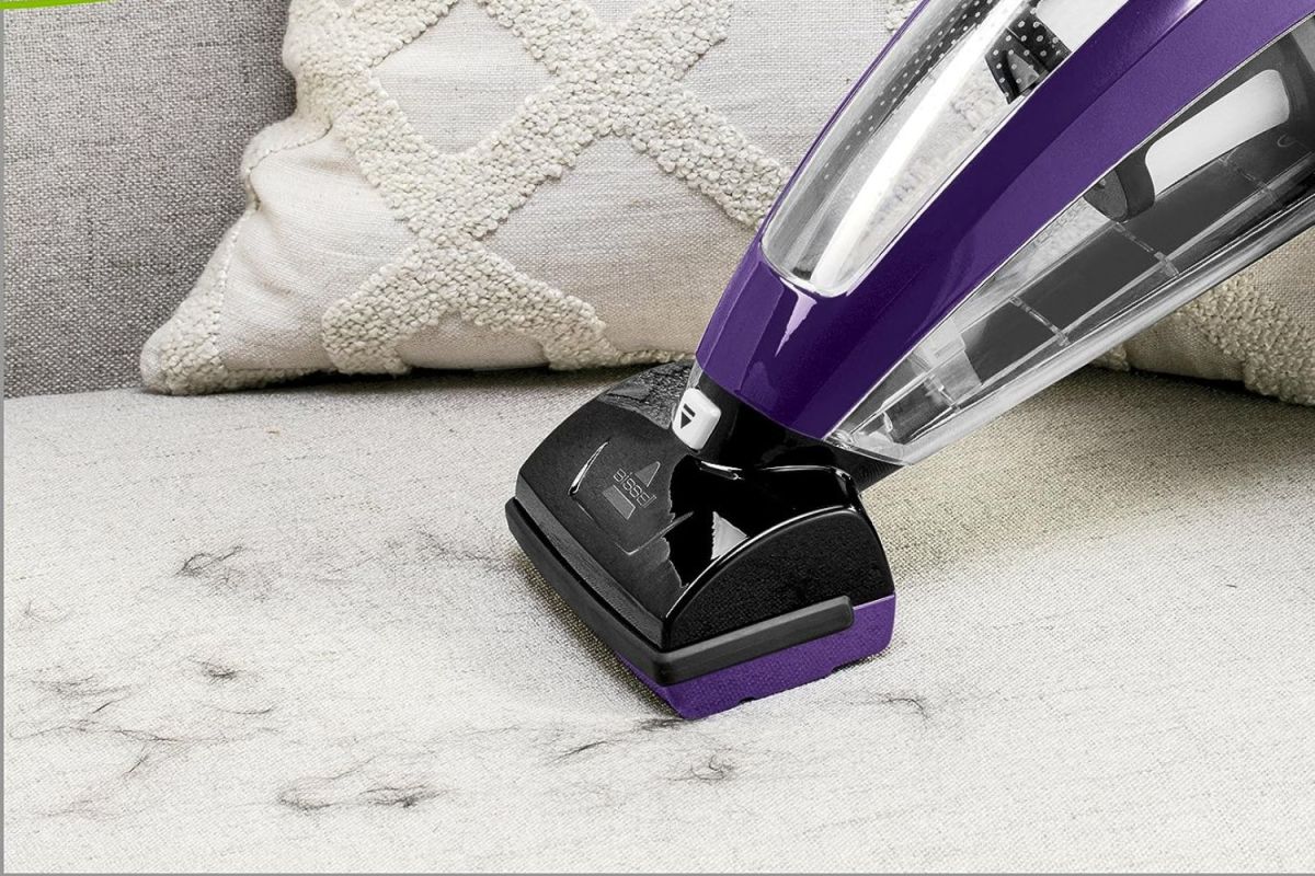 A person using the best handheld vacuum for pet hair to clean pet hair off a couch.