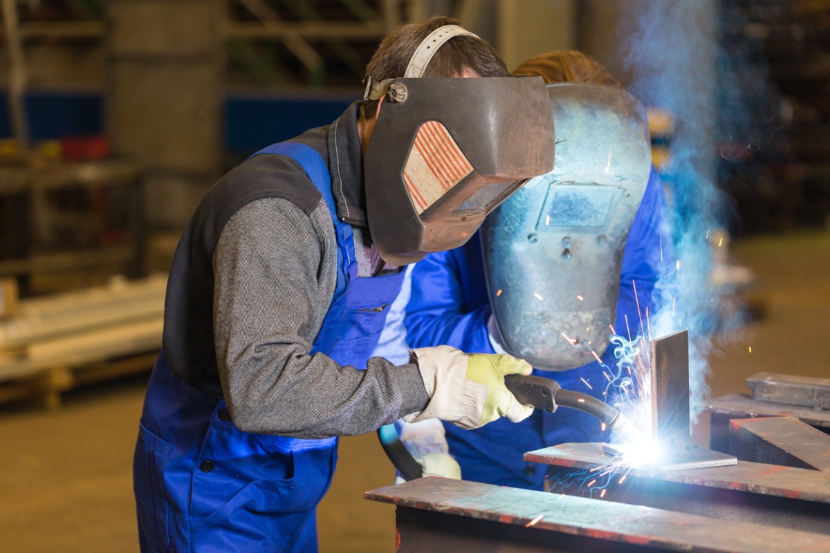 A welder in blue overalls at work.
