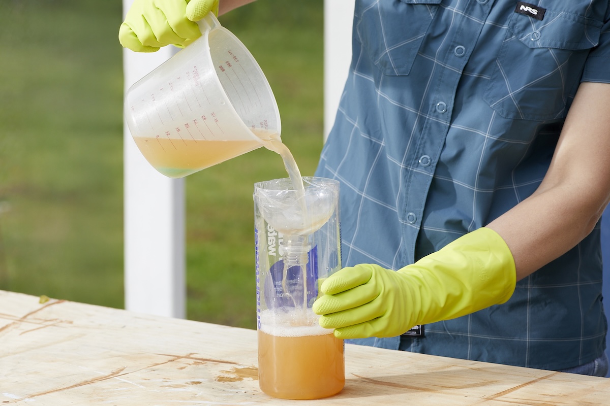 Woman pours wasp-killing solution into wasp trap.