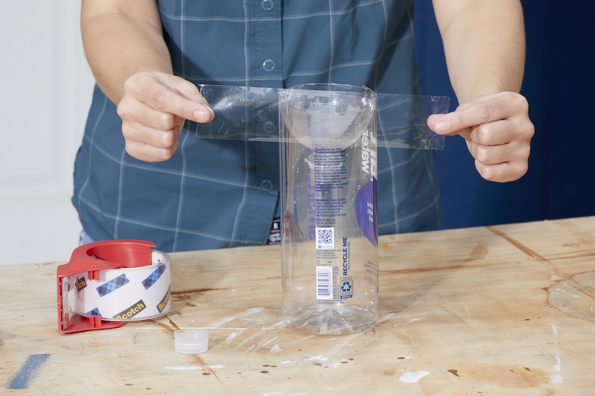 Woman inverts bottle top into bottle and tapes with shipping tape.