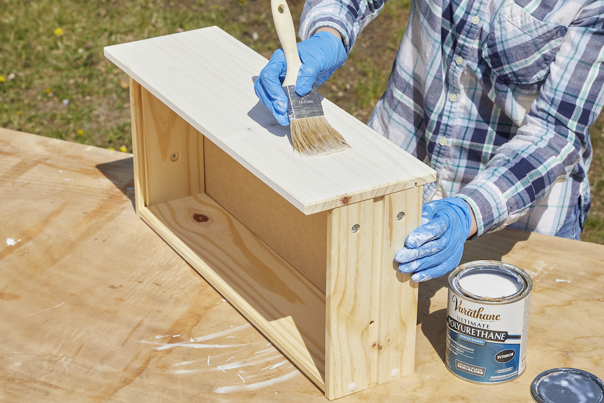 Woman seals a whitewashed dresser drawer with polyurethane.