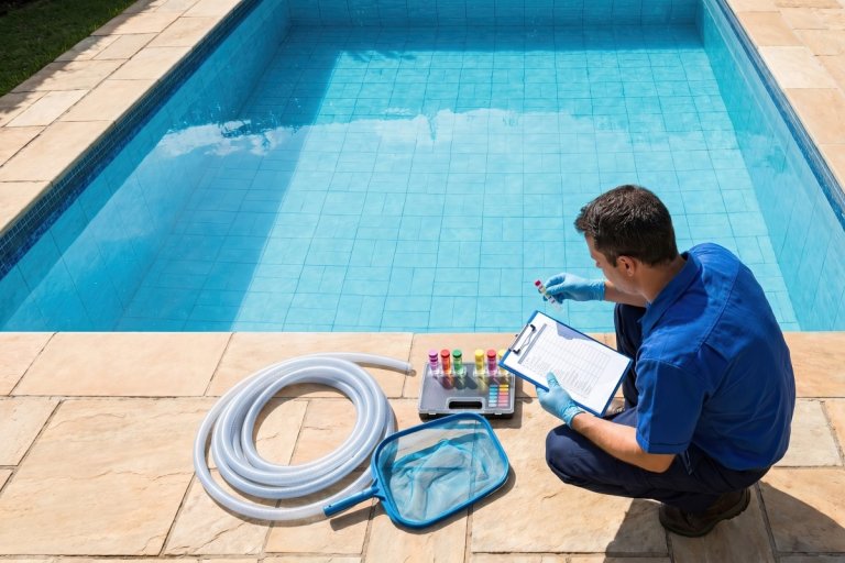 A person is checking pool water quality with various tools and equipment.