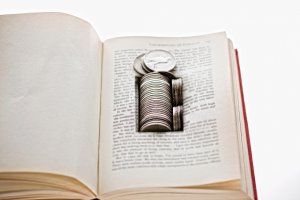 Old silver coins hidden in space cut into the leaves of a book.