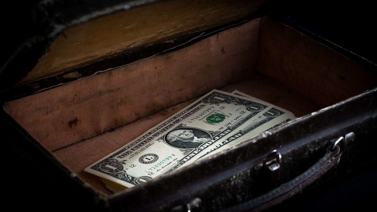 Hidden stack of cash in empty suitcase.