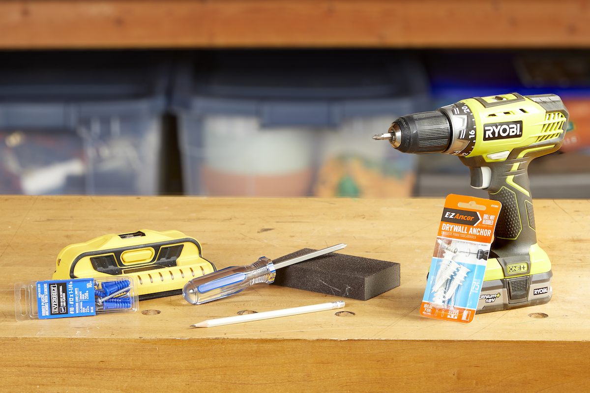 Materials needed to insert drywall anchors into a wall, including a level and a drill.