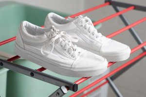 Clean white sneakers are drying on a drying rack.