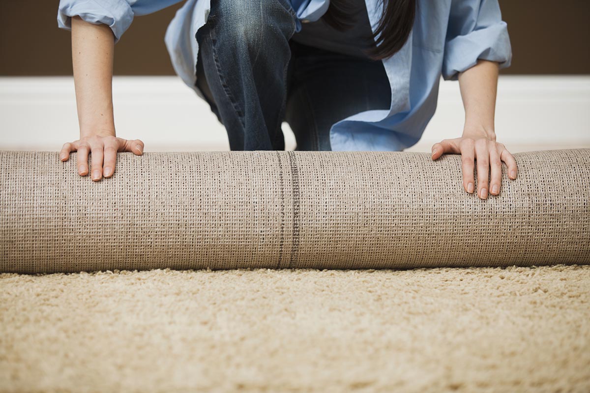 A close up of a person rolling out a carpet.
