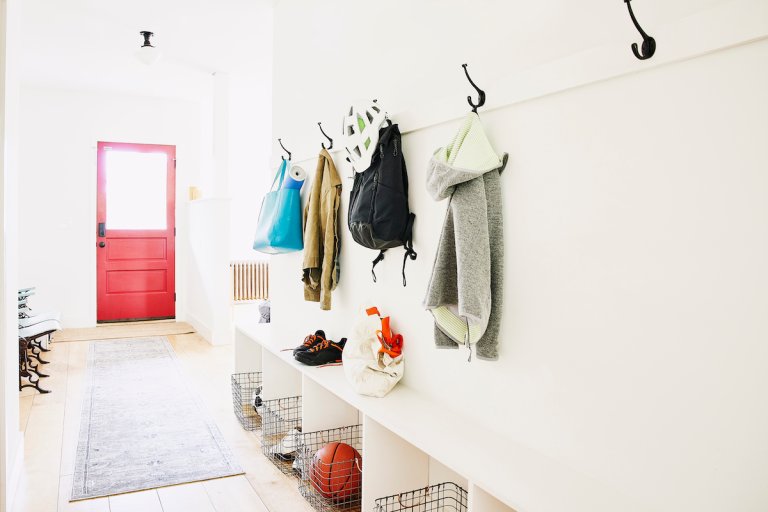 Wide shot of coats bags and shoes in entryway of home with a red front door.