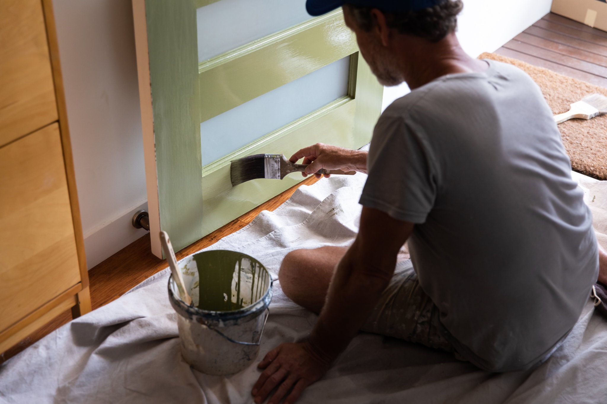 Person paints the front door in a pale green color