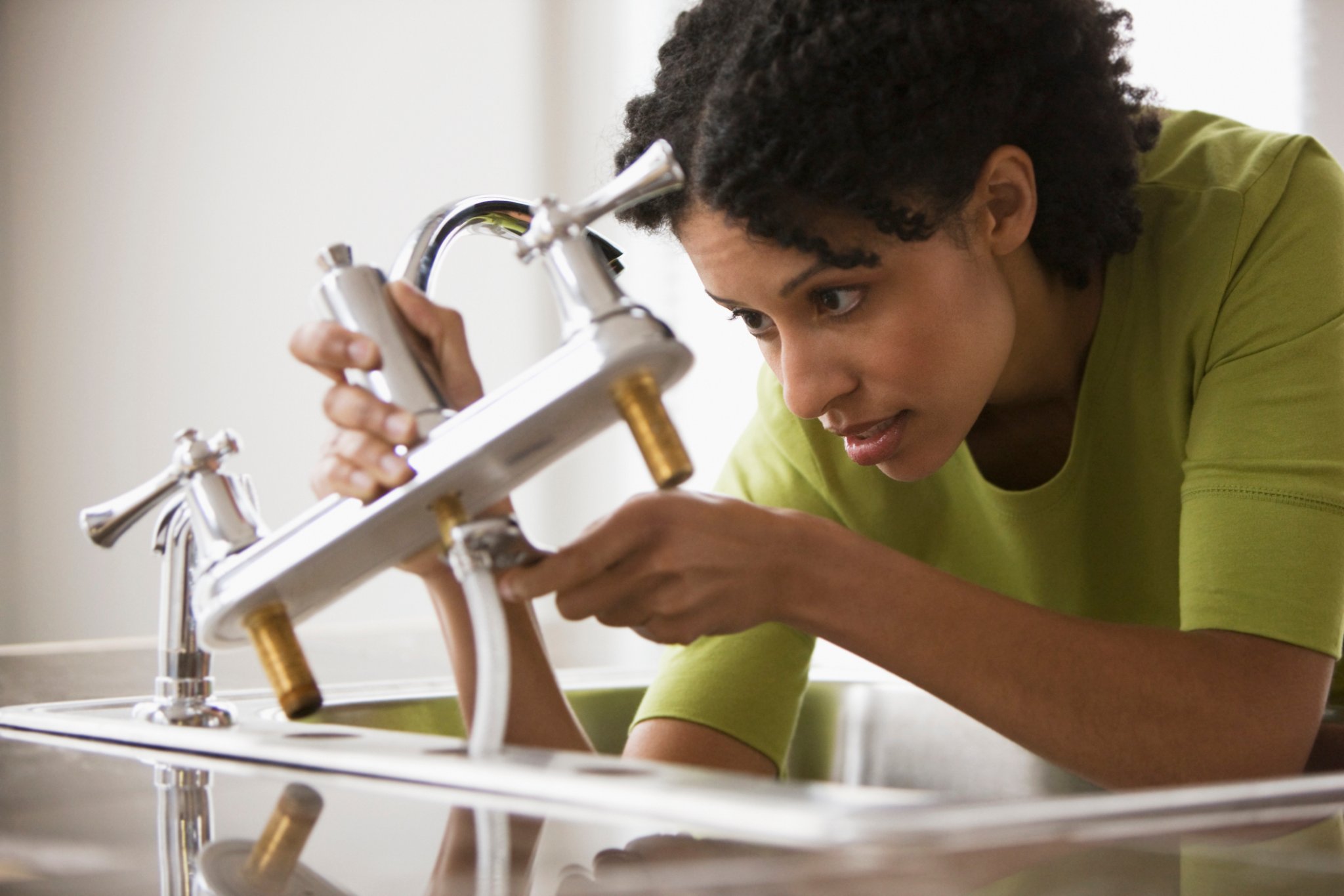 A person installs a new kitchen faucet