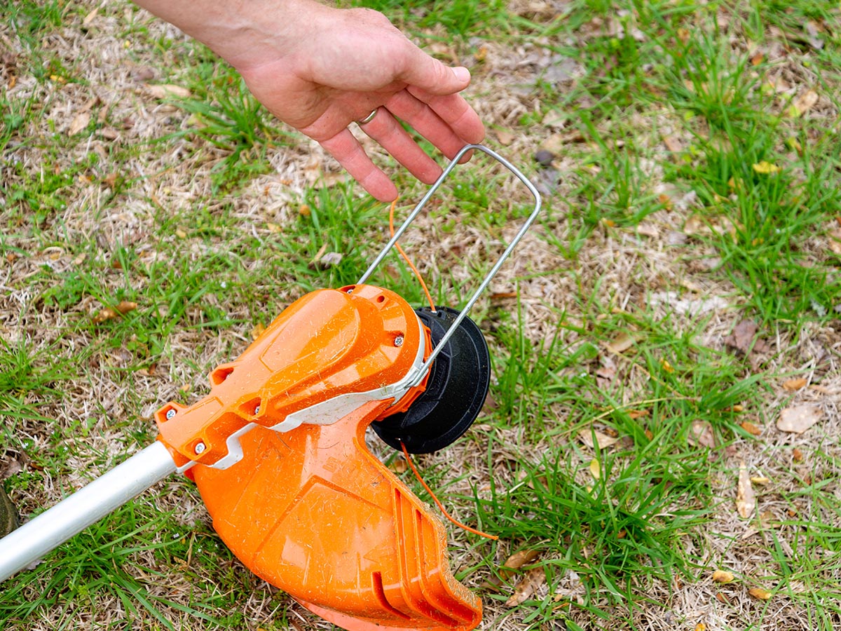 Hand holding the metal guard on a Stihl weed eater
