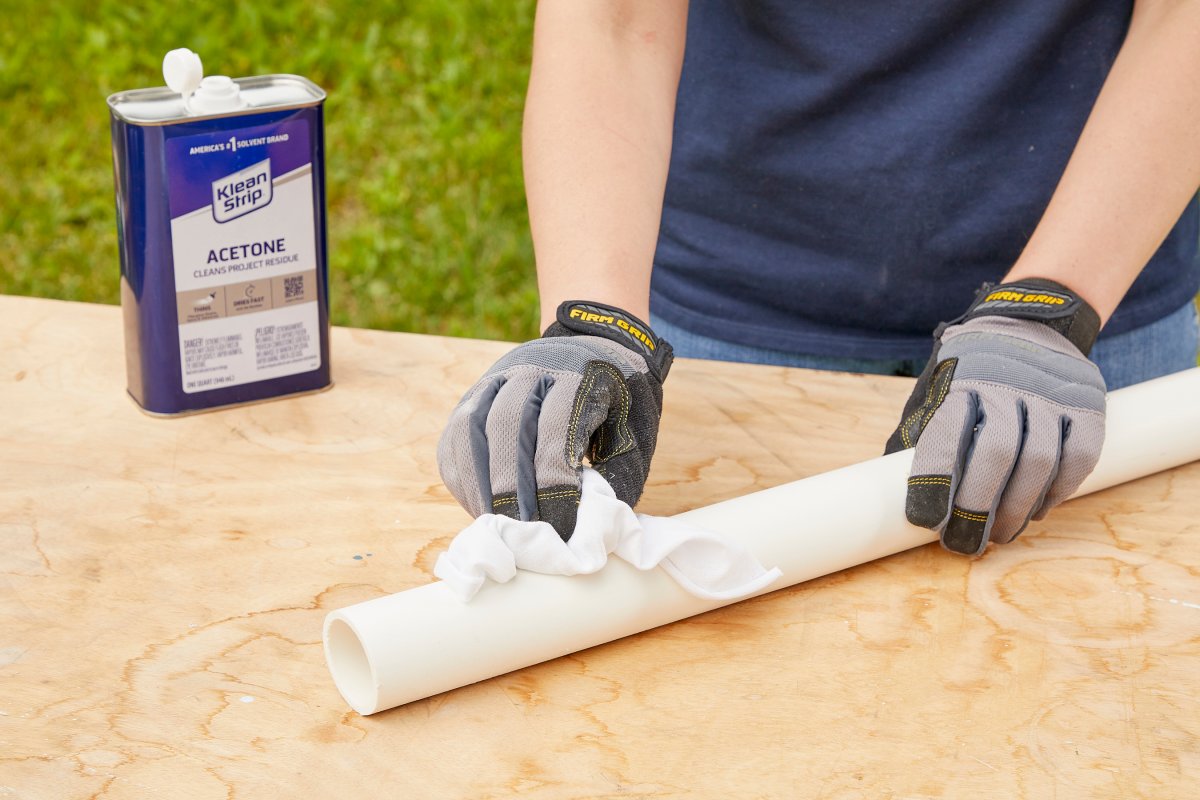 Woman uses a cloth with acetone to clean the surface of a PVC pipe.