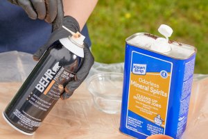 Woman cleans spray paint applicator with paint thinner.