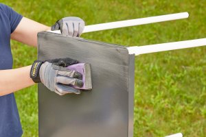 Woman uses sanding block to sand a metal table.