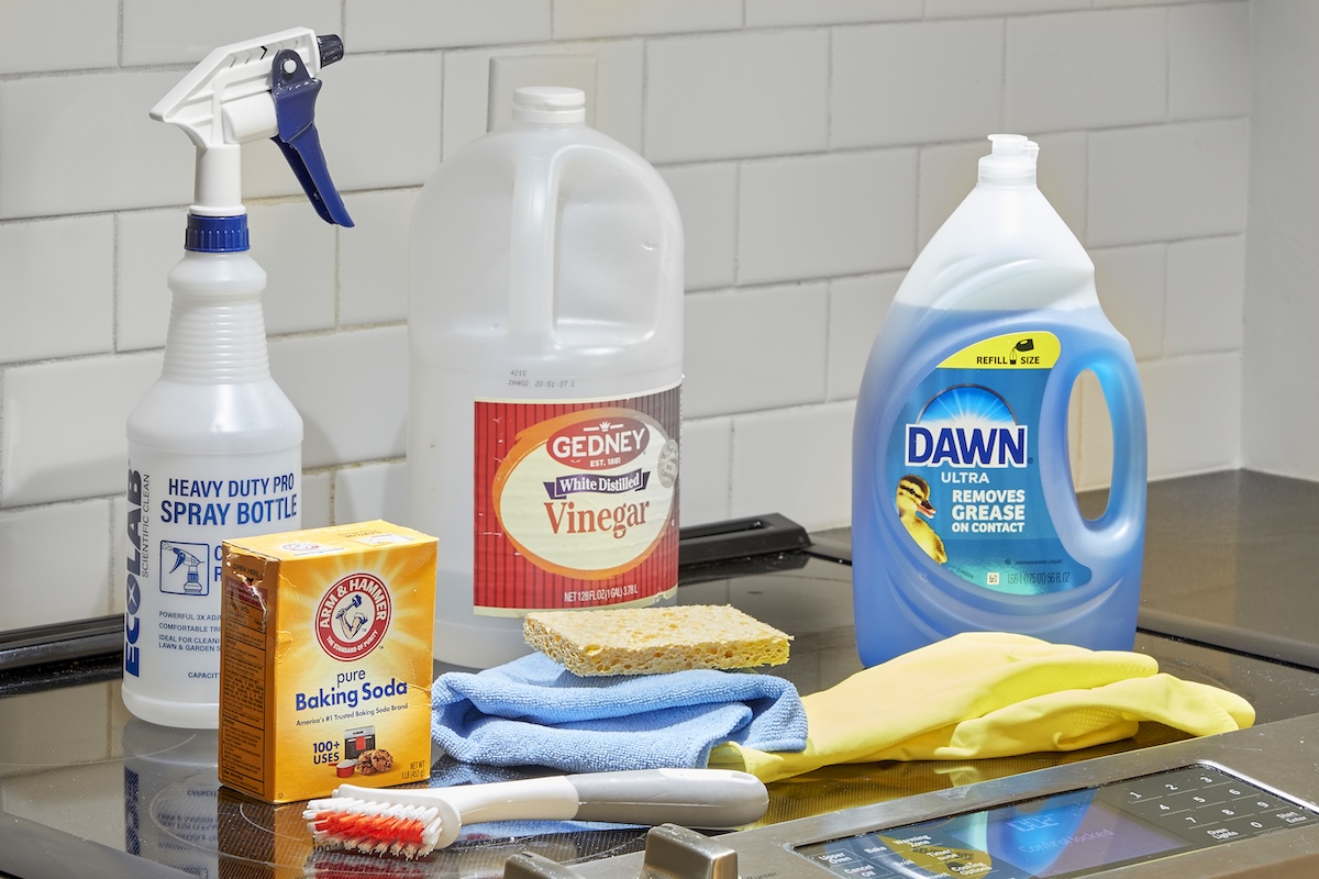 Materials needed for cleaning a range hood filter, including dish soap, vinegar, a spray bottle, and baking soda.