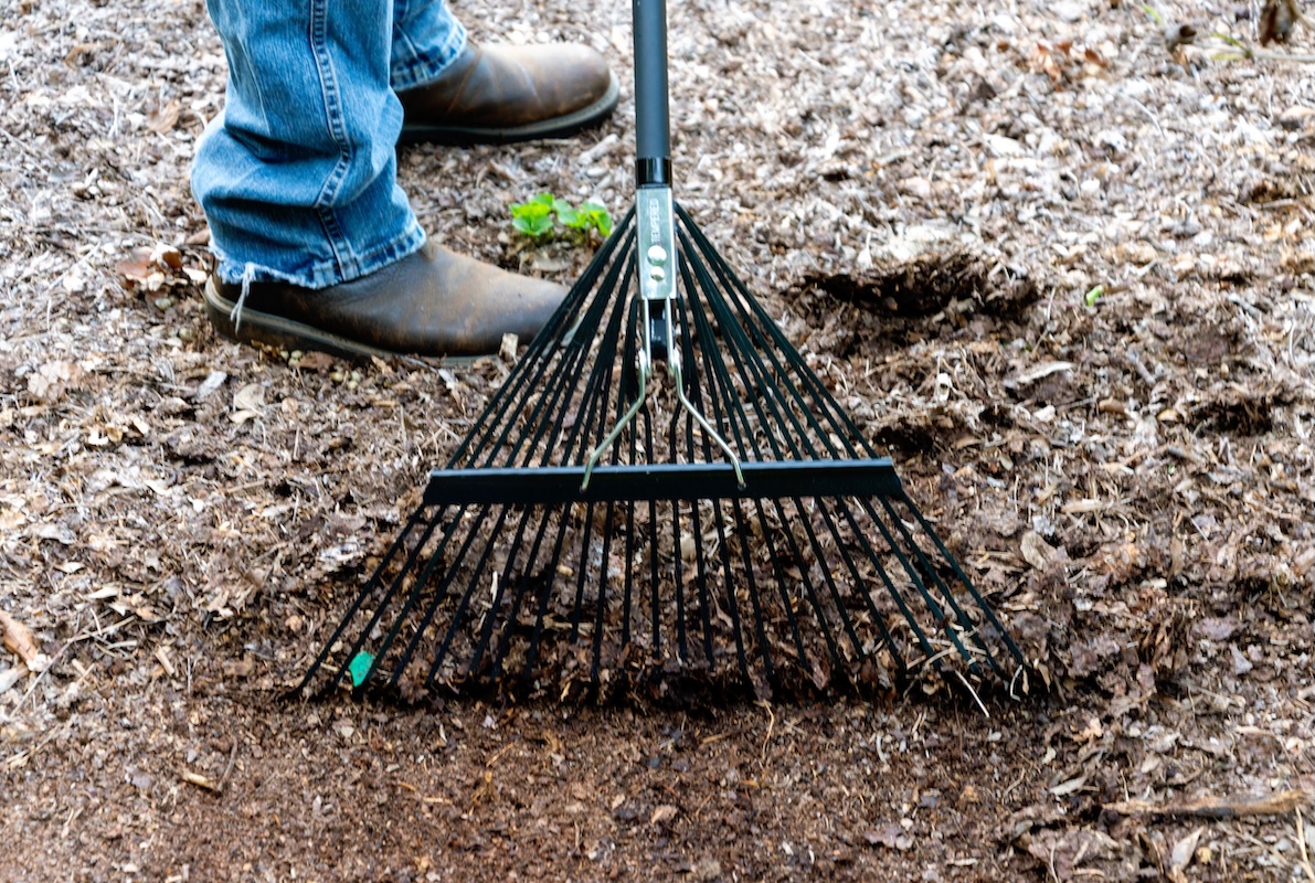 Closeup of the black Razorback rake's head, along with a man's jeans and shoes.