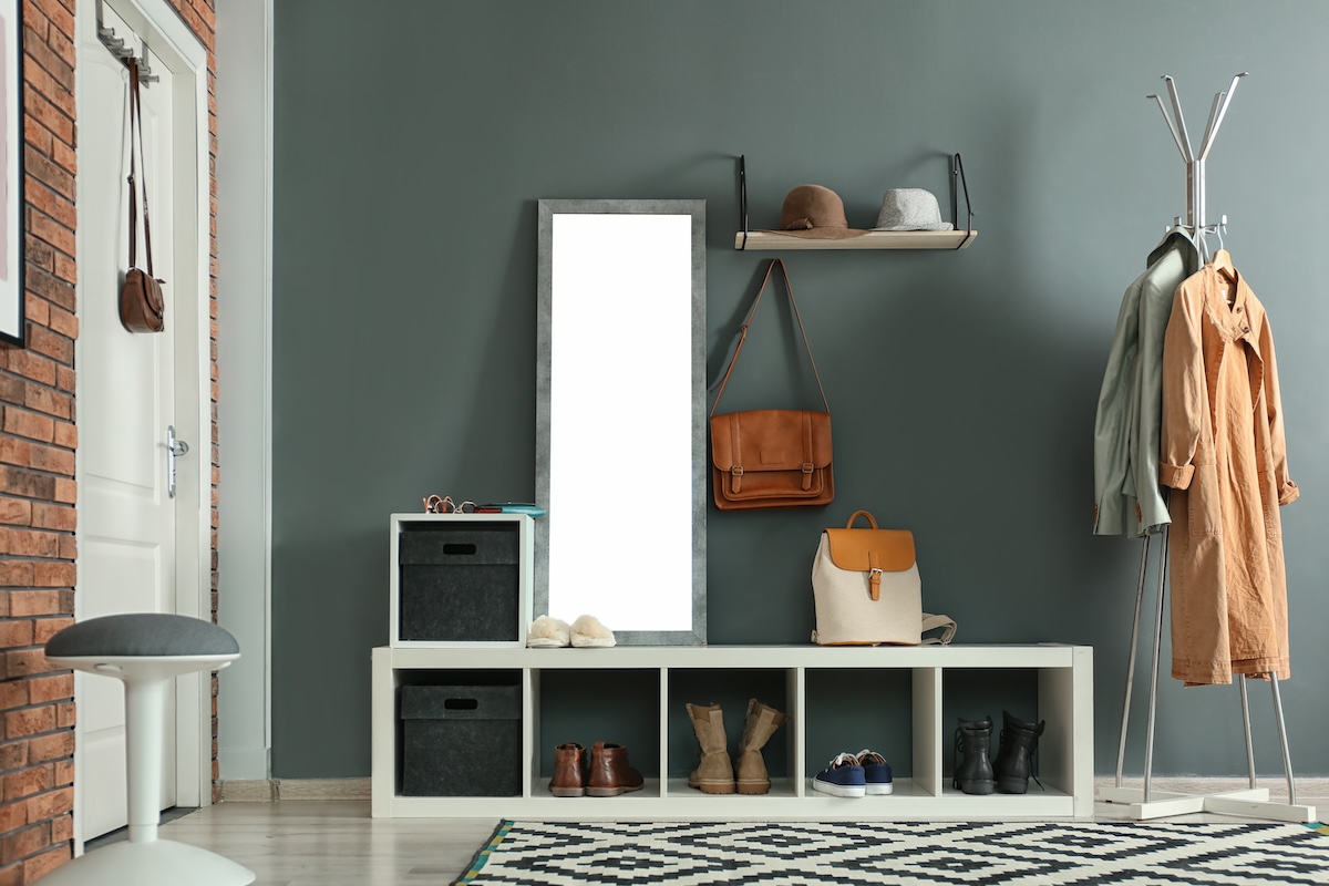 Hallway organizer with bench, mirror, rug, and blue/grey paint on the walls.