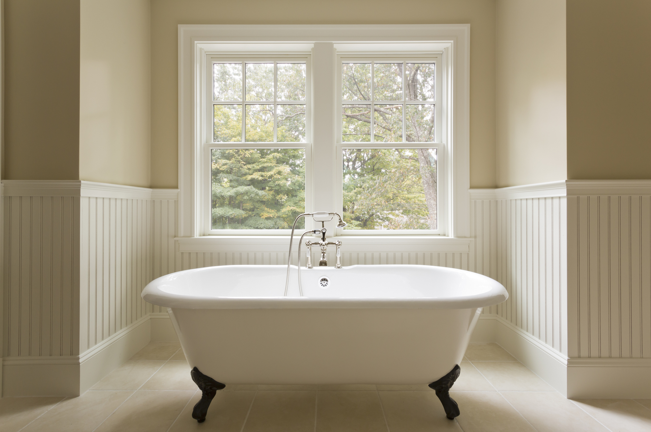 Clawfoot bathtub in modern looking white and cream bathroom.