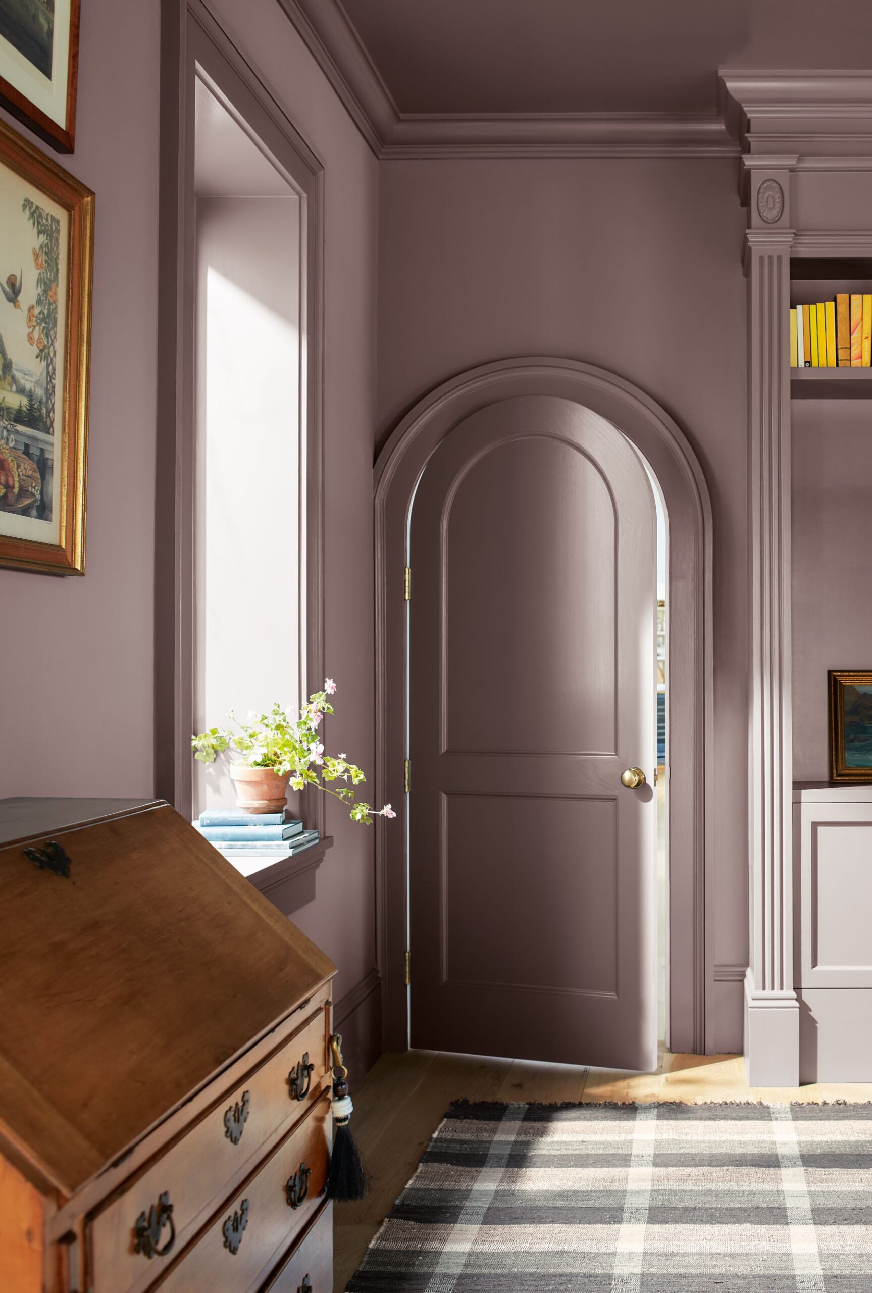 Benjamin Moore's Cinnamon Slate color-drenching an office with ornate trim work around a rounded door and a large window