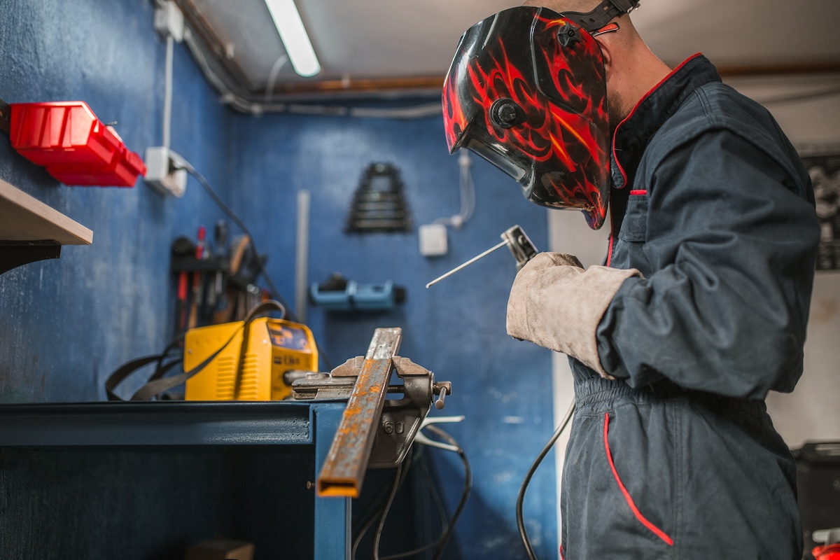 A person learning how to weld in their home workshop using a stick welder.