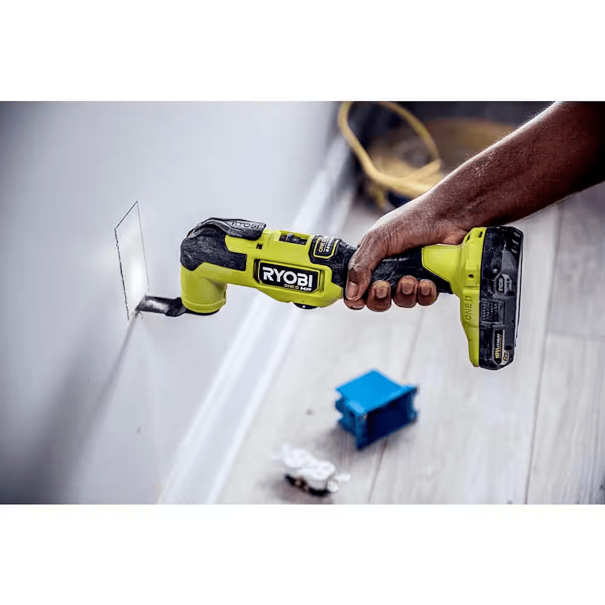 A person using an oscillating tool to cut a hole in drywall.