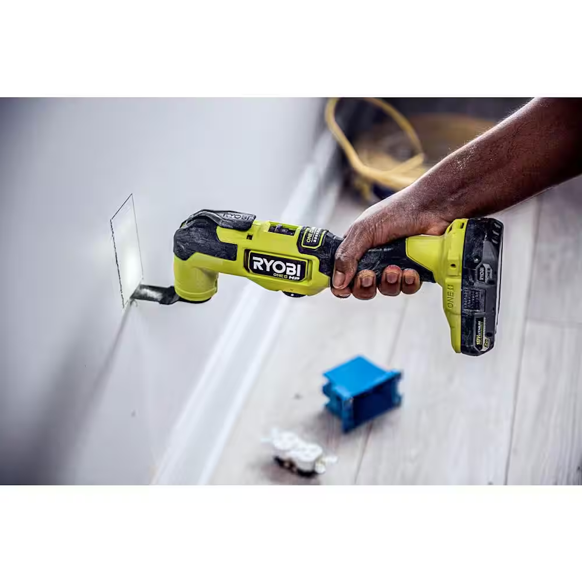A person using an oscillating tool to cut a hole in drywall.