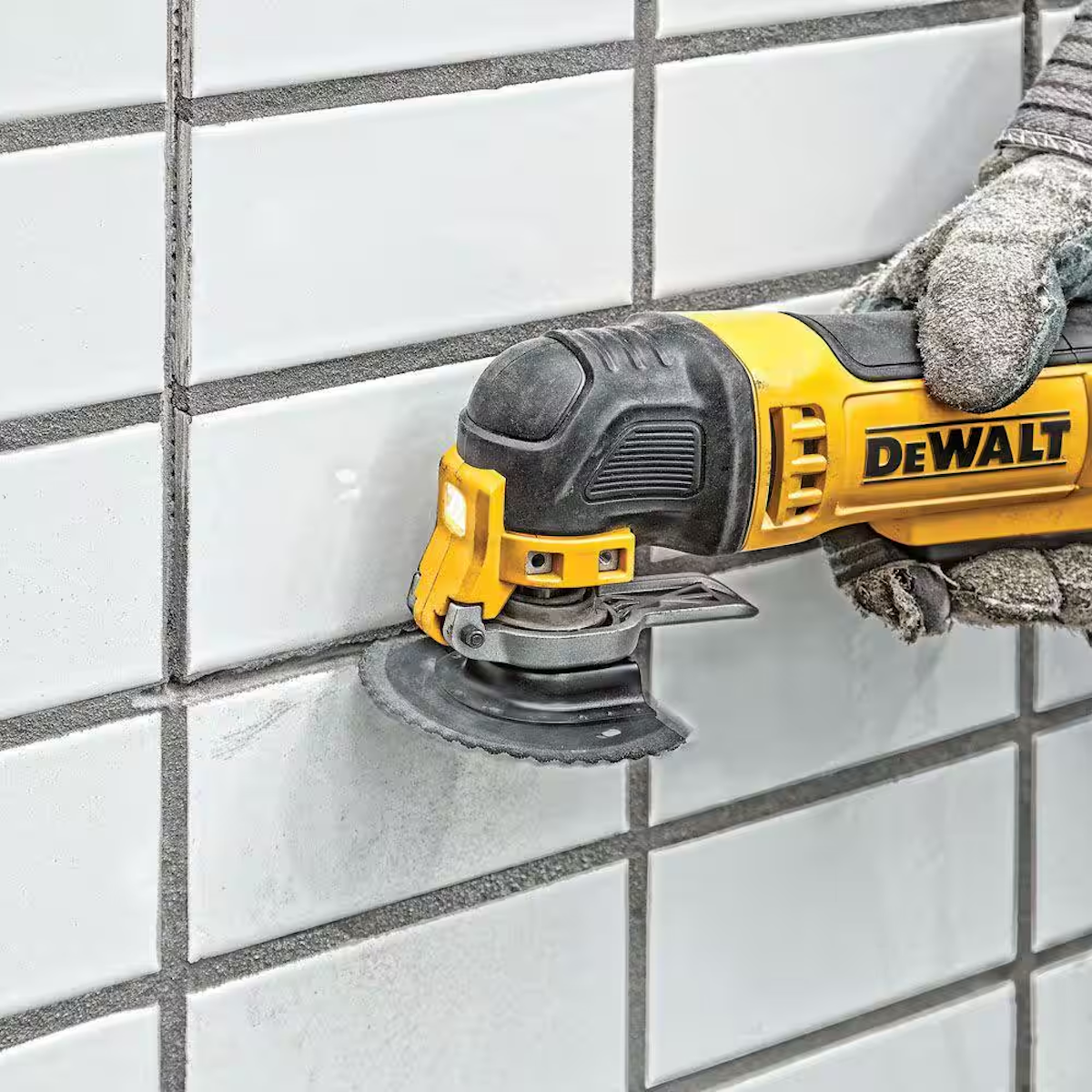 A person using an oscillating tool to remove grout around tiles.