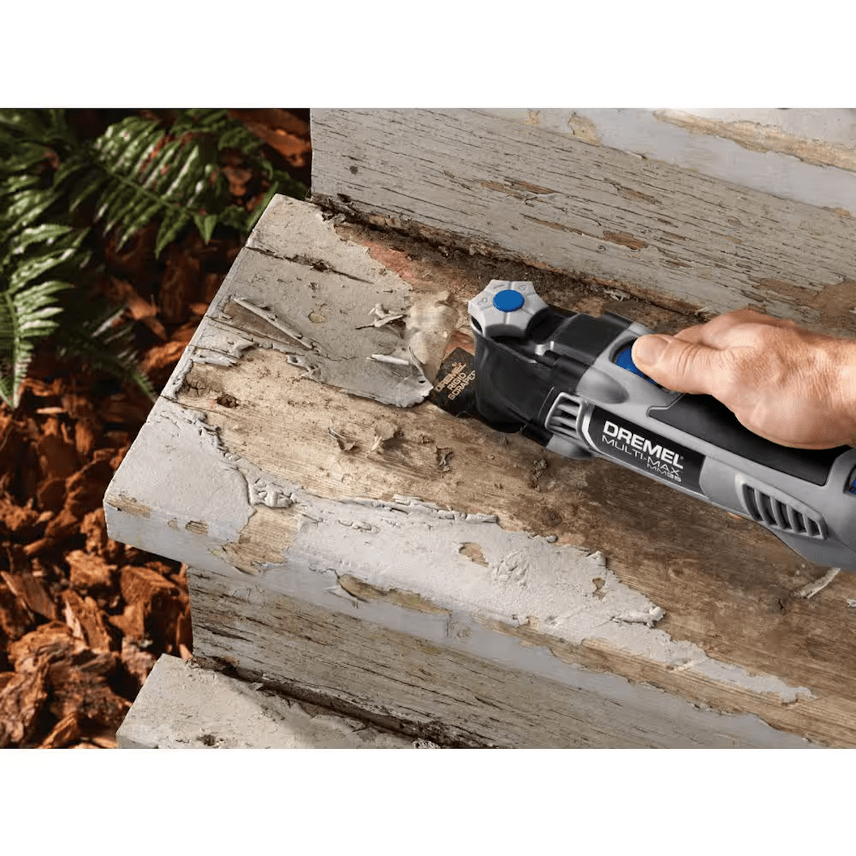 A person using an oscillating tool to scrape and remove paint from stairs.