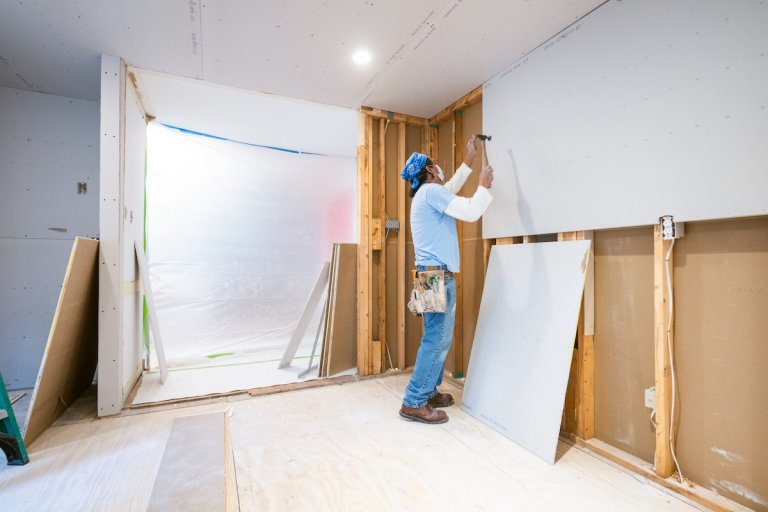 A DIYer installing drywall in a home basement with bathroom.