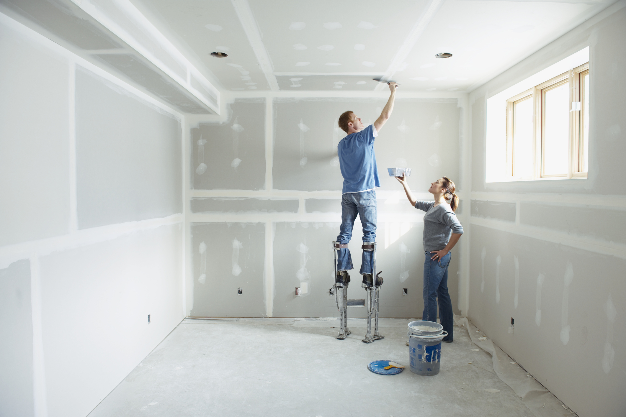 Woman and man painting an empty room in their house.