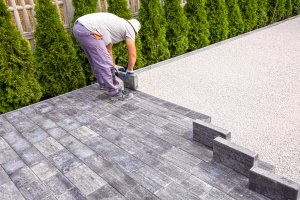 Man laying paving stones on a driveway.