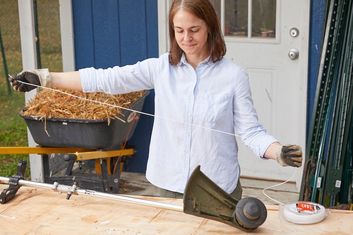 Woman measures string for string trimmer by holding the string in the span of her arms.