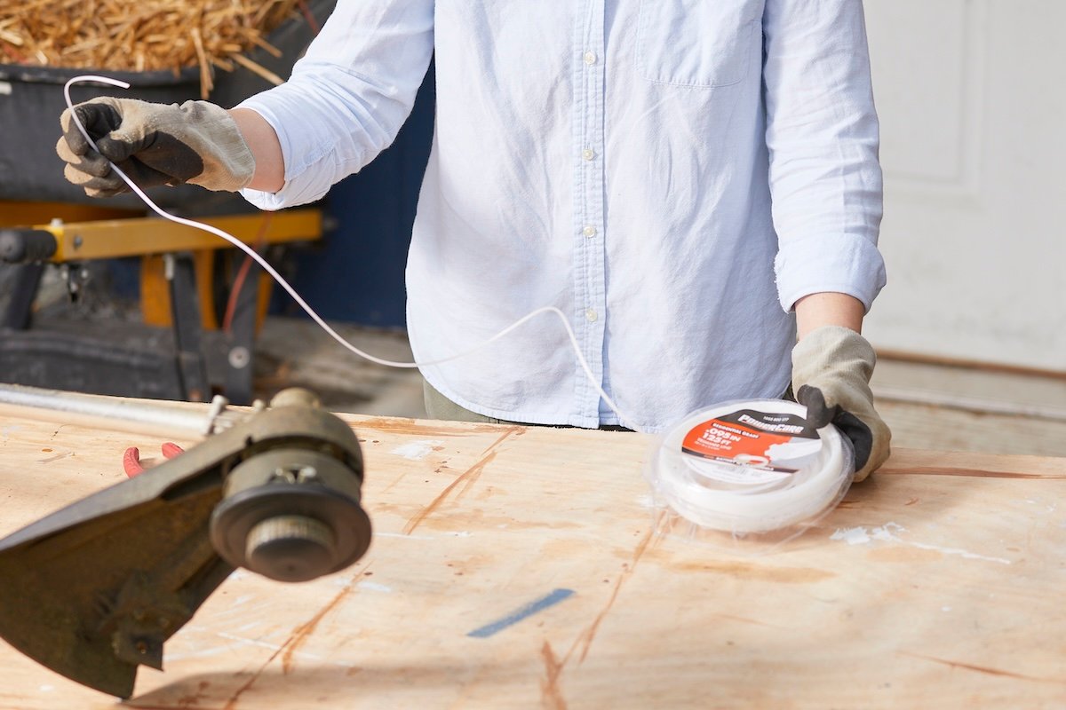 Woman examines white string from a spool before installing in a string feeder.
